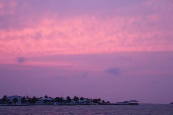 Pastel mor bir gün batımı Karayipler 'deki sessiz bir adanın üzerinde gökyüzünü boyar..