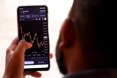 Genç bir çocuk telefon çekiminde borsa teftişi yapıyor.