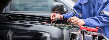 Bir teknisyen araba aküsünü kontrol ediyor..