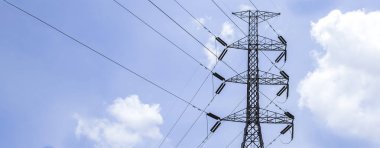 High voltage poles with sky and clouds in the background.