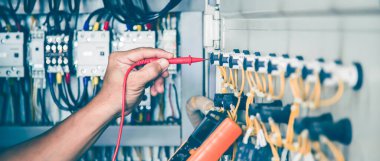 Elektrik mühendisi elektrik kontrol kabinesinin bakımını düzenli olarak test ediyor.