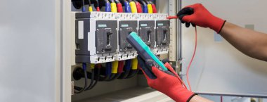 Elektrik mühendisi elektrik kontrol kabinesinin bakımını düzenli olarak test ediyor.