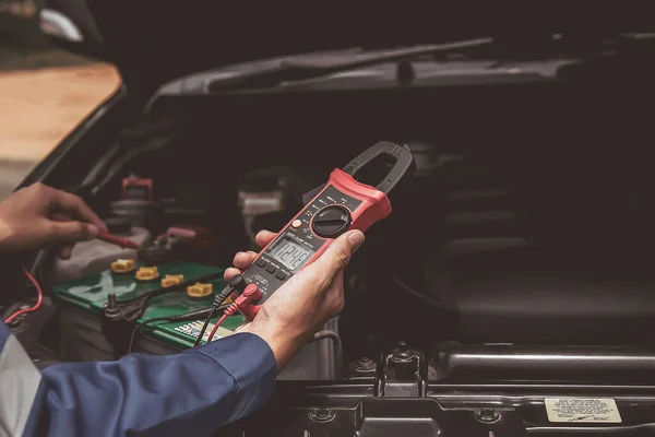 stock image A technician is checking the car battery for availability.