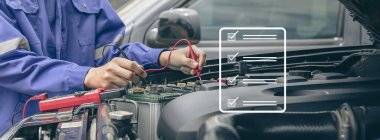 Bir teknisyen araba aküsünü kontrol ediyor..