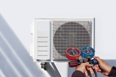 Klima, havalandırma servis teknisyeni soğutucu ve soğutucu eklemek için göstergeler kullanıyor..