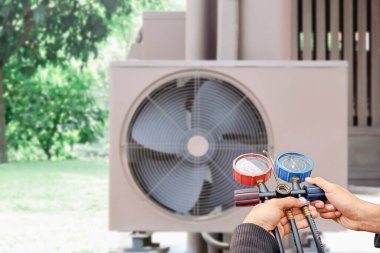 Klima, havalandırma servis teknisyeni soğutucu ve soğutucu eklemek için göstergeler kullanıyor..