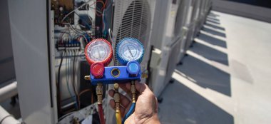 Klima, havalandırma servis teknisyeni soğutucu ve soğutucu eklemek için göstergeler kullanıyor..