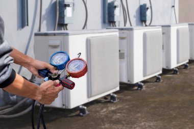 Klima, havalandırma servis teknisyeni soğutucu ve soğutucu eklemek için göstergeler kullanıyor..