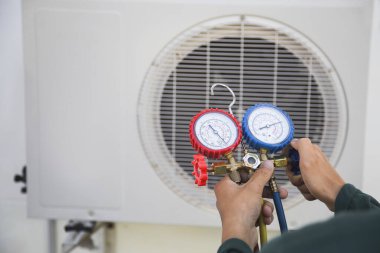 Klima, havalandırma servis teknisyeni soğutucu ve soğutucu eklemek için göstergeler kullanıyor..