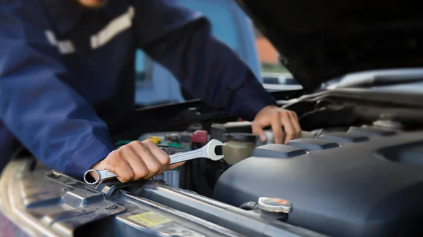 The mechanic works on the engine of the car in the garage, car repair service.