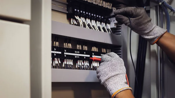 Electrical engineer tests the operation of the electric control cabinet on a regular basis for maintenance.