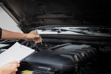 Otomobil tamircisi, kontrol panosuna denetim yazısıyla bir otomobil motorunu kontrol ediyor. Onarım makinesi, araba servisi ve bakım listesi..