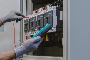 Elektrik mühendisi elektrik kontrol kabinesinin bakımını düzenli olarak test ediyor.