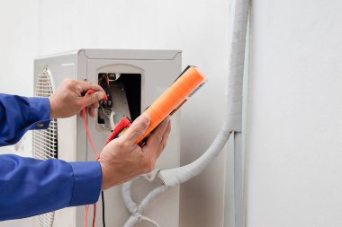 Klimayı, ölçüm ekipmanlarını, soğutucuyu denetleyen teknisyen.