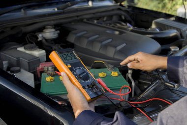 Bir teknisyen araba aküsünü kontrol ediyor..