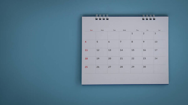 White calendar laying on blue background planning concept.