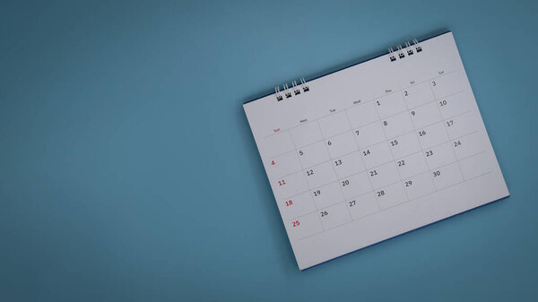 White calendar laying on blue background planning concept.
