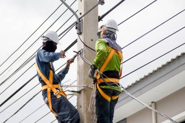 Elektrik teknisyenleri elektrik direğine bağlı kablolar üzerinde çalışıyorlar
