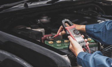 Bir teknisyen araba aküsünü kontrol ediyor..