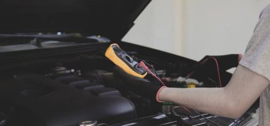 Bir teknisyen araba aküsünü kontrol ediyor..