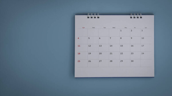 White calendar laying on blue background planning concept.