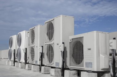 Mavi gökyüzü ve bulutları olan endüstriyel bir binanın çatısında havalandırma (HVAC).