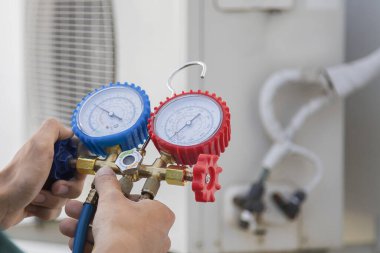 Air conditioning, HVAC service technician using gauges to check refrigerant and add refrigerant. clipart