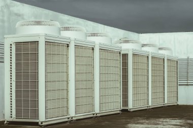 Mavi gökyüzü ve bulutları olan endüstriyel bir binanın çatısında havalandırma (HVAC).