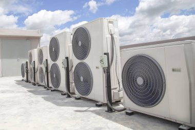 Mavi gökyüzü ve bulutları olan endüstriyel bir binanın çatısında havalandırma (HVAC).