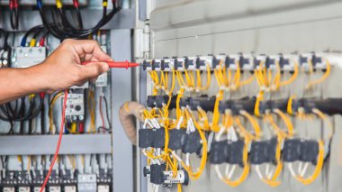 Elektrik mühendisi elektrik kontrol kabinesinin bakımını düzenli olarak test ediyor.