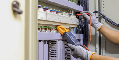 Elektrik mühendisi elektrik kontrol kabinesinin bakımını düzenli olarak test ediyor.