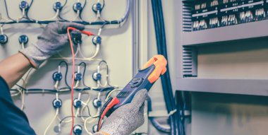 Elektrik mühendisi elektrik kontrol kabinesinin bakımını düzenli olarak test ediyor.