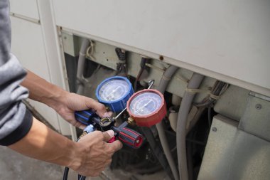 Klima, havalandırma servis teknisyeni soğutucu ve soğutucu eklemek için göstergeler kullanıyor..