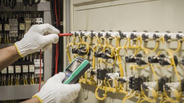 Elektrik mühendisi elektrik kontrol kabinesinin bakımını düzenli olarak test ediyor.