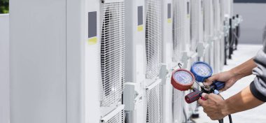 Klima, havalandırma servis teknisyeni soğutucu ve soğutucu eklemek için göstergeler kullanıyor..