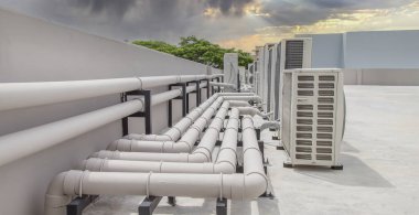 Mavi gökyüzü ve bulutları olan endüstriyel bir binanın çatısında havalandırma (HVAC).