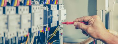 Elektrik mühendisi elektrik kontrol kabinesinin bakımını düzenli olarak test ediyor.