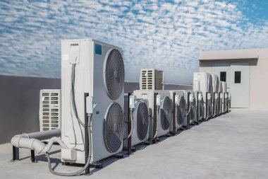 Mavi gökyüzü ve bulutları olan endüstriyel bir binanın çatısında havalandırma (HVAC).