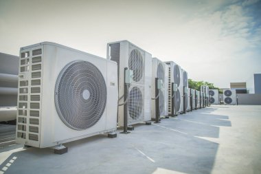 Mavi gökyüzü ve bulutları olan endüstriyel bir binanın çatısında havalandırma (HVAC).