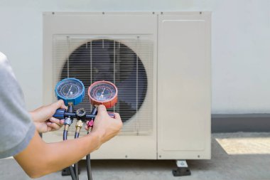 Klima, havalandırma servis teknisyeni soğutucu ve soğutucu eklemek için göstergeler kullanıyor..