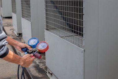 Hava tamircisi endüstriyel klimaları doldurmak için ölçüm aletleri kullanıyor..