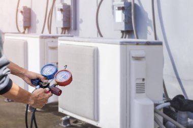 Hava tamircisi endüstriyel klimaları doldurmak için ölçüm aletleri kullanıyor..