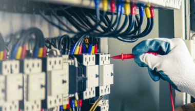 Electrical engineer checking the operation of electrical control cabinet, maintenance concept.