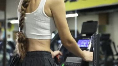 Spor salonunda eliptik yürüyüş makinesiyle egzersiz yapan bir kadın. Yürüyüş makinesinde beden eğitimi gören kız..