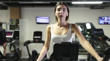 Spor salonunda eliptik yürüyüş makinesiyle egzersiz yapan bir kadın. Yürüyüş makinesinde beden eğitimi gören kız..