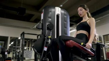 Sağlık, fitness ve vücut geliştirme konsepti. Genç ve çekici bir kız spor salonunda bacak kaslarını çalıştırıyor..