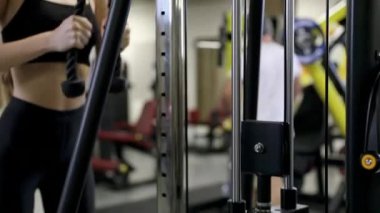 Sağlık, fitness ve vücut geliştirme konsepti. Spor salonunda kaslarını ve trisepslerini şişiren genç atletik kadın.
