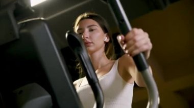 Spor salonunda eliptik yürüyüş makinesiyle egzersiz yapan bir kadın. Yürüyüş makinesinde beden eğitimi gören kız..