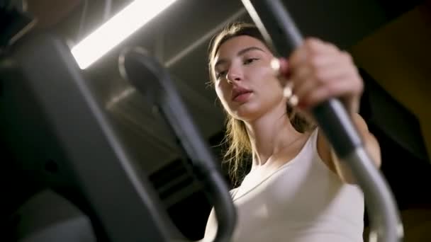 ジムで楕円歩行機械で運動する女性 ウォーキングマシンでフィットネスガールトレーニング — ストック動画