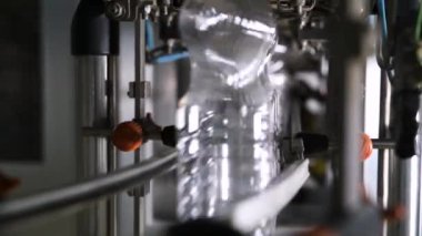  Plastik şişe üretimi. PET şişesi ya da plastik şişe üfleme makinesi. Boru hattından geçen plastik konteynırlar.